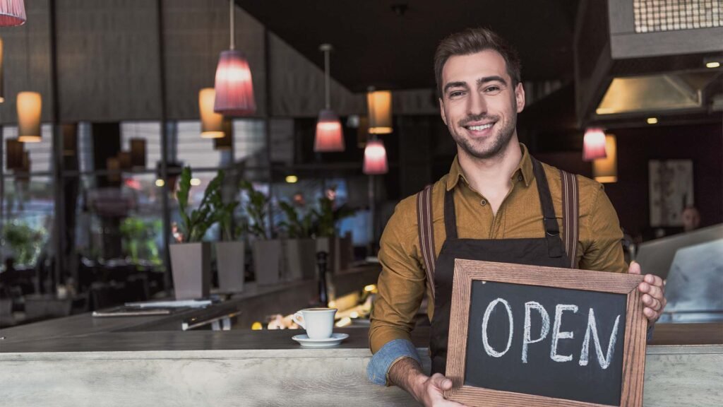 Image of man holding open sign of restaurant